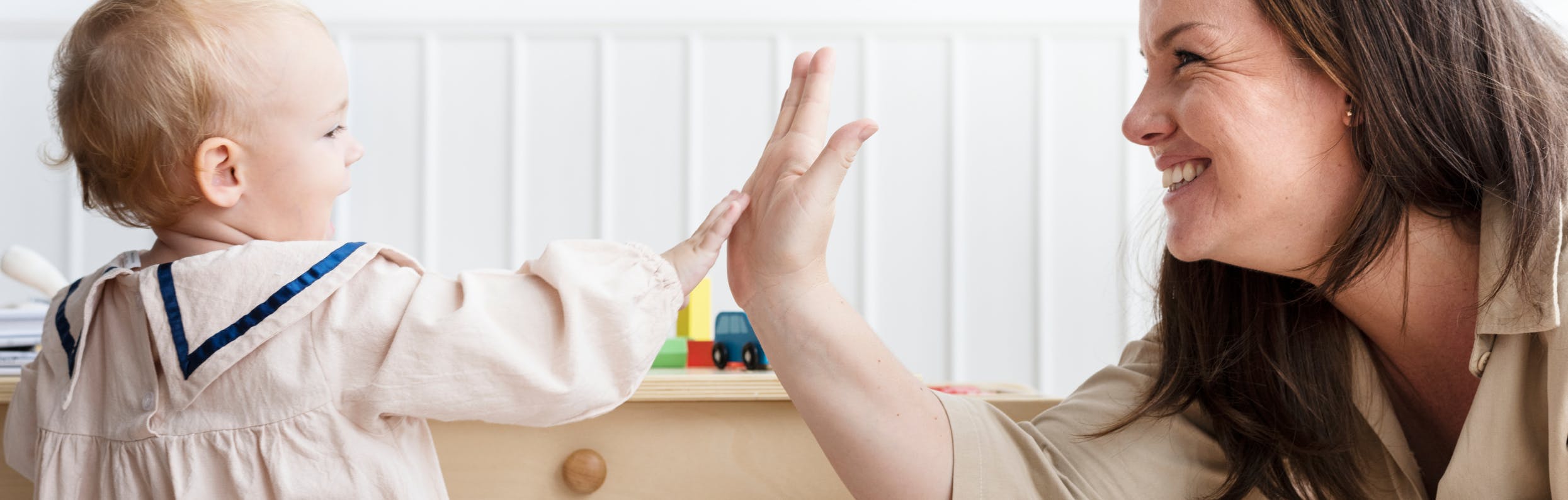 A baby giving a high five to a caregiver